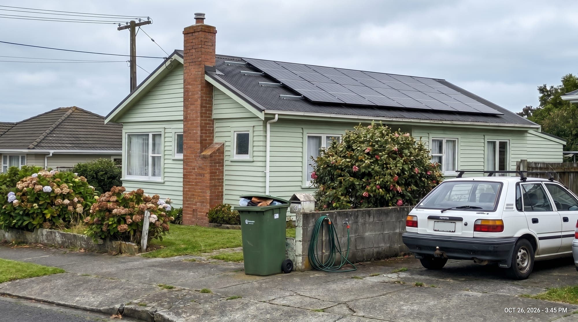 Workers installing solar panels on a corrugated iron roof in New Zealand with speech bubble asking what does solar actually cost